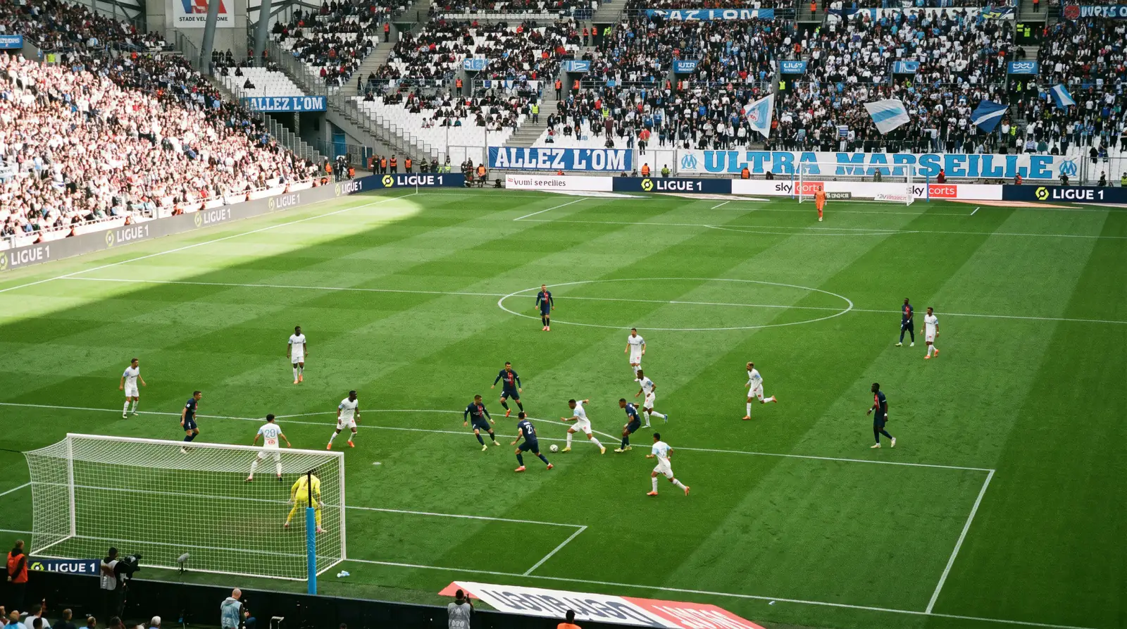 Deux équipes de football s'affrontant sur un terrain de Ligue 1 avec les deux buts visibles