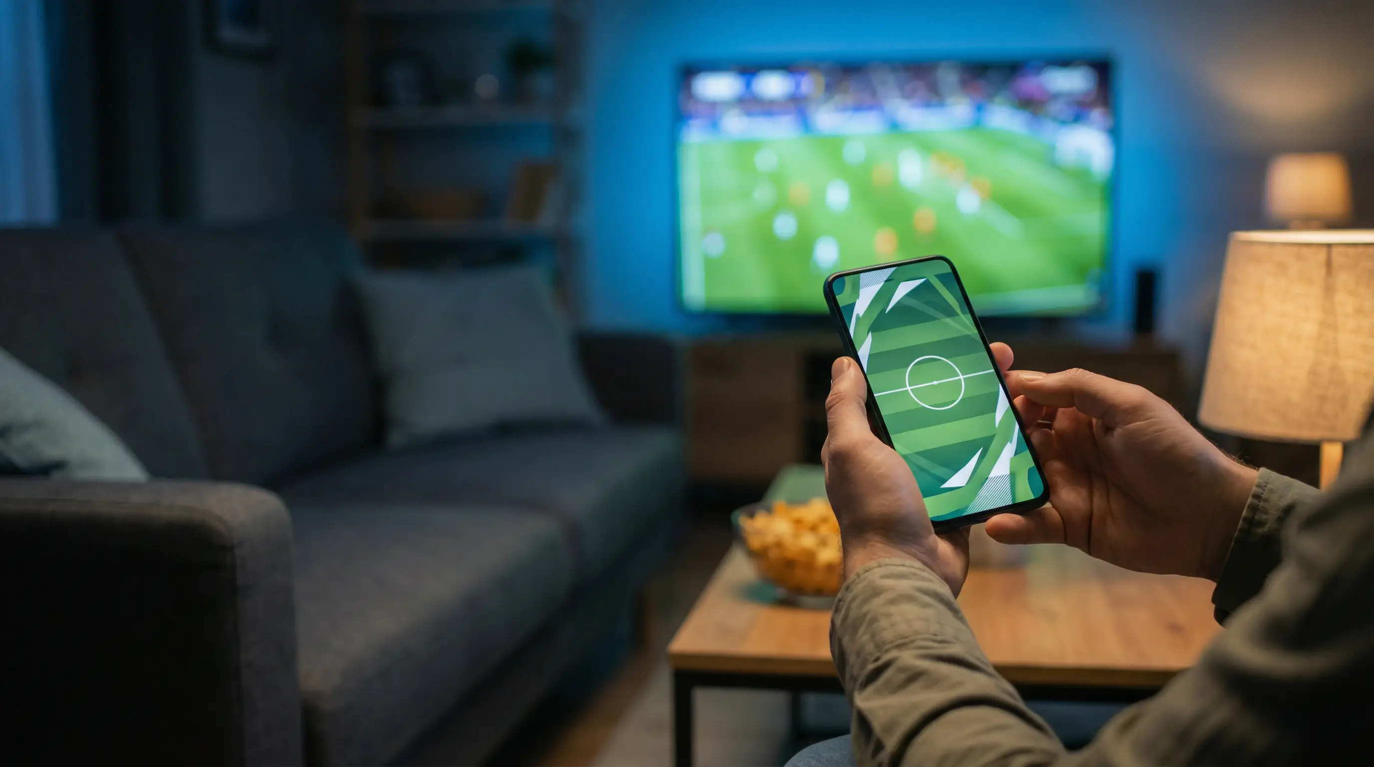 Supporter regardant un match de football en direct sur smartphone avec application de paris sportifs