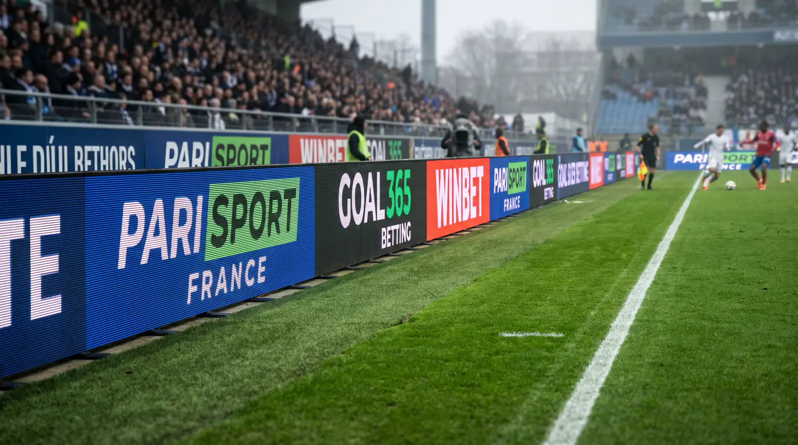 Panneaux publicitaires de paris sportifs le long d'un terrain de football français